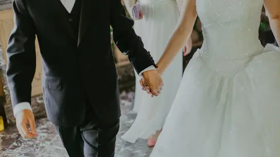 Unos novios cogidos de la mano en su boda Unos novios cogidos de la mano en su boda