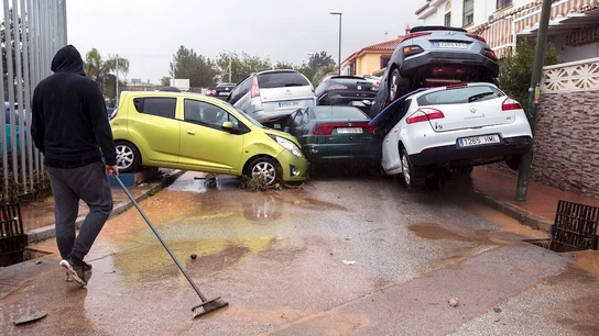 Un hombre limpia la zona y observa los coches amontonados en Málaga Un hombre limpia la zona y observa los coches amontonados en Málaga