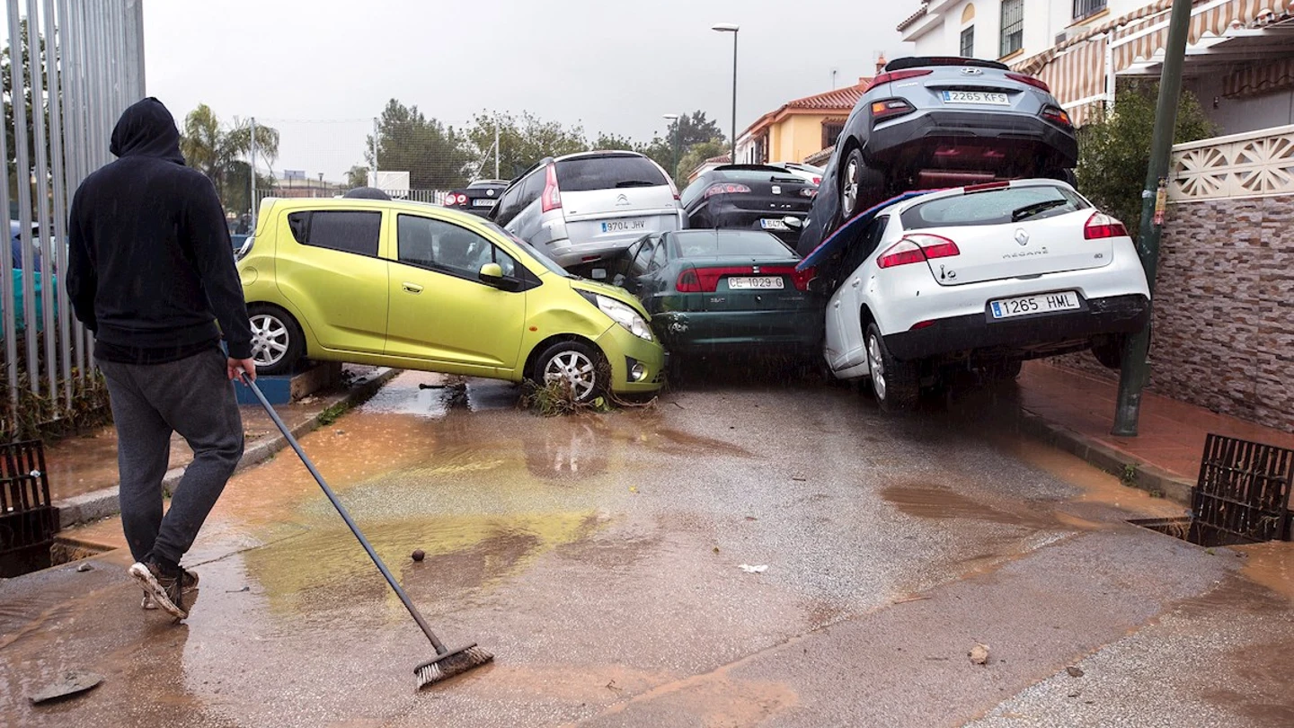 Un hombre limpia la zona y observa los coches amontonados en Málaga Un hombre limpia la zona y observa los coches amontonados en Málaga
