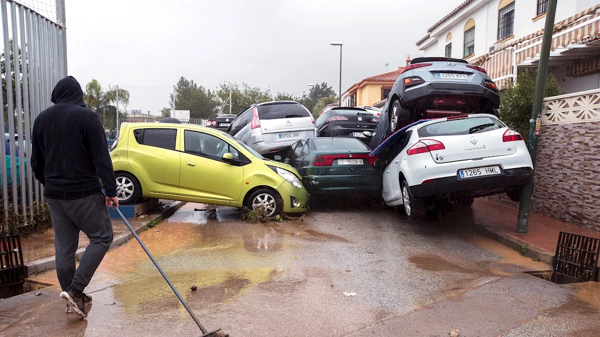 Un hombre limpia la zona y observa los coches amontonados en Málaga