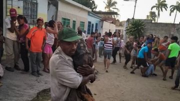 Un hombre carga con uno de los niños quemados tras el incendio en la ciudad de Cagua (Venezuela)
