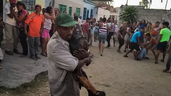 Un hombre carga con uno de los niños quemados tras el incendio en la ciudad de Cagua (Venezuela)