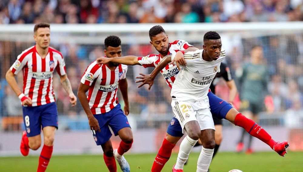 Los jugadores brasileños Vinícius Jr. (d) del Real Madrid y Renan Lodi del Atlético de Madrid, disputan un balón
