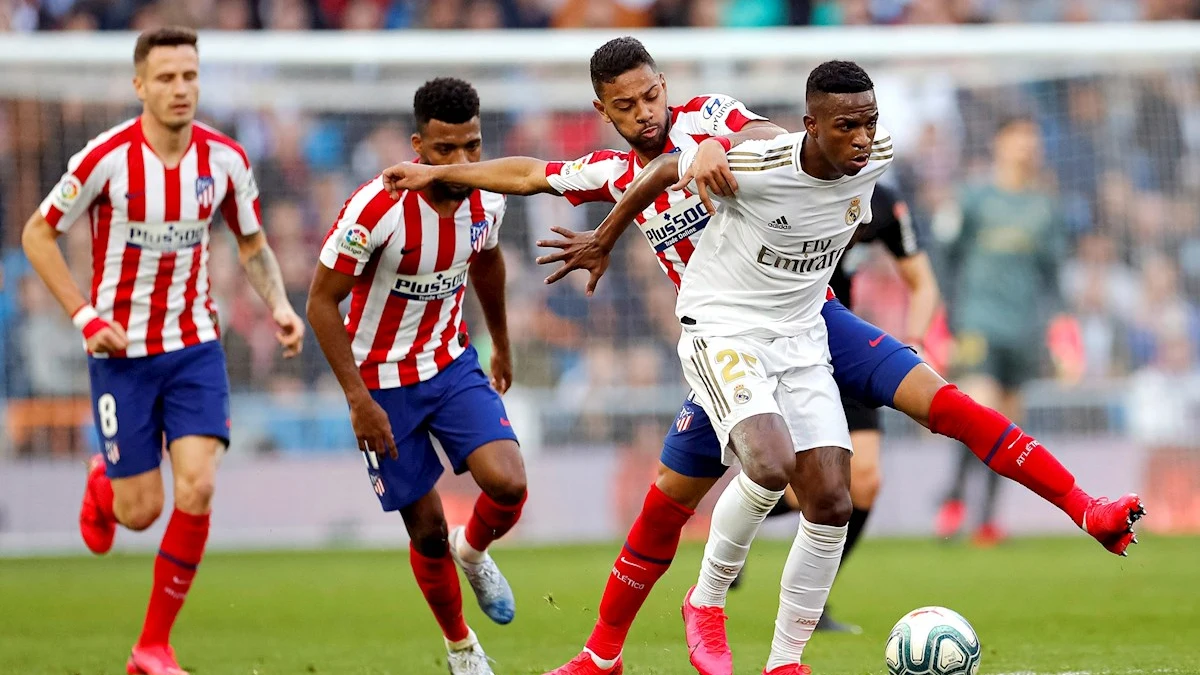 Los jugadores brasileños Vinícius Jr. (d) del Real Madrid y Renan Lodi del Atlético de Madrid, disputan un balón 