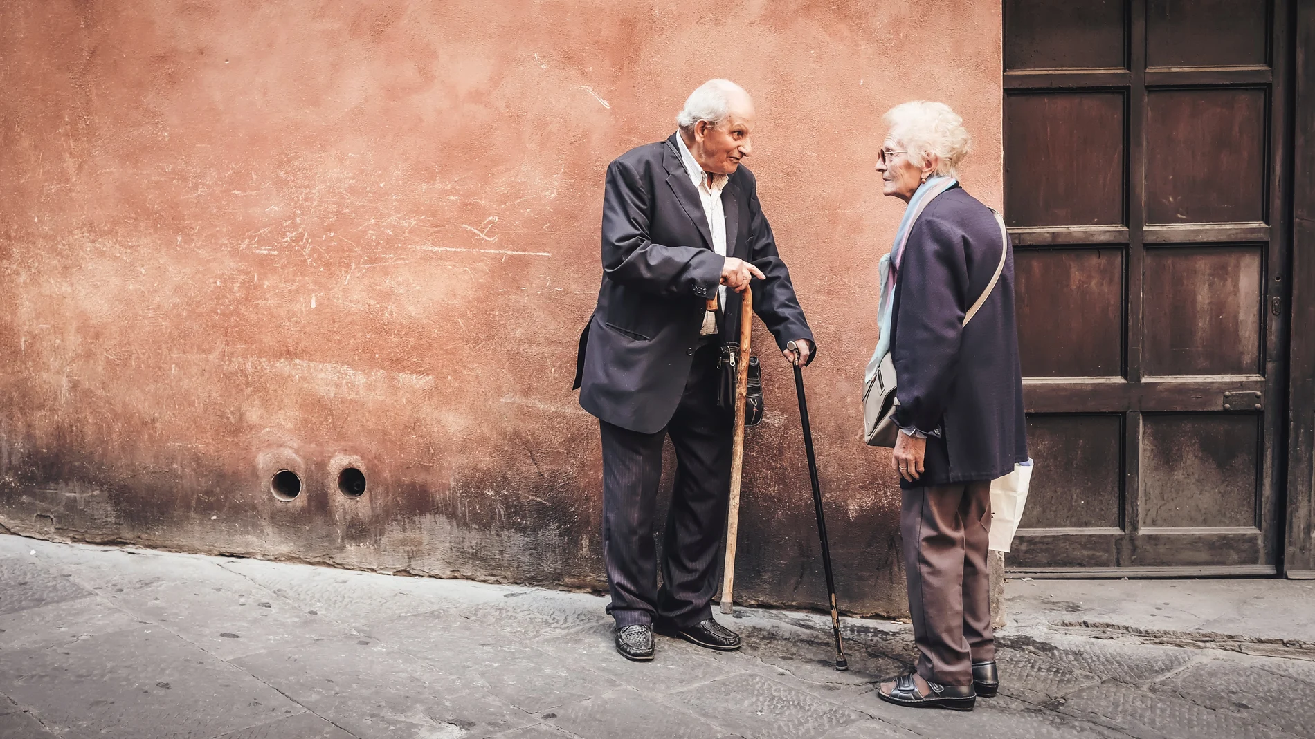 Dos ancianos frente a un domicilio