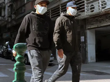 Dos personas pasean con mascarillas en Macao Dos personas pasean con mascarillas en Macao