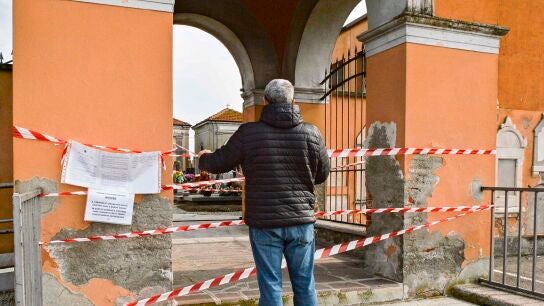 Un ciudadano observa un cementerio cerrado por el coronavirus