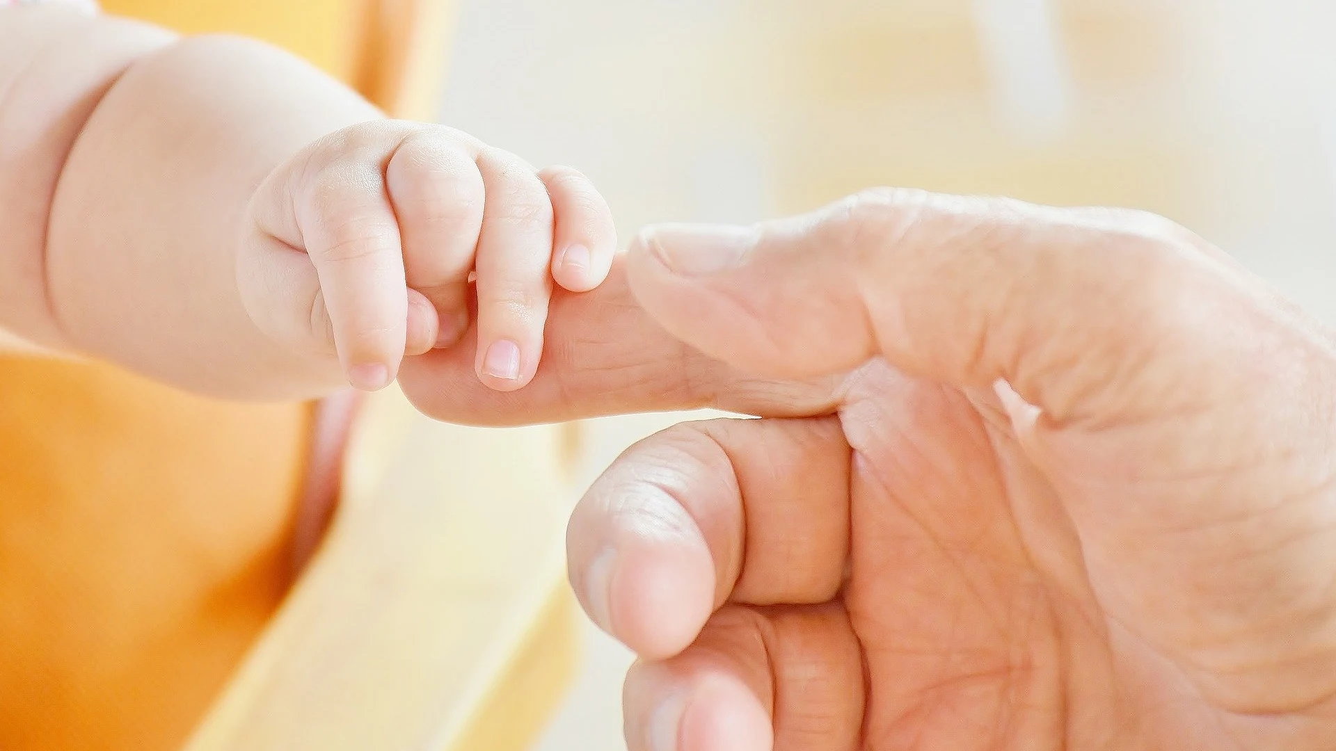 Imagen de archivo de un bebé cogiendo la mano de un adulto. 