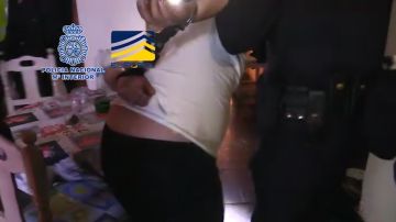 Un agente se lleva esposado a uno de los detenidos de una organización que explotaba a mujeres rumanas