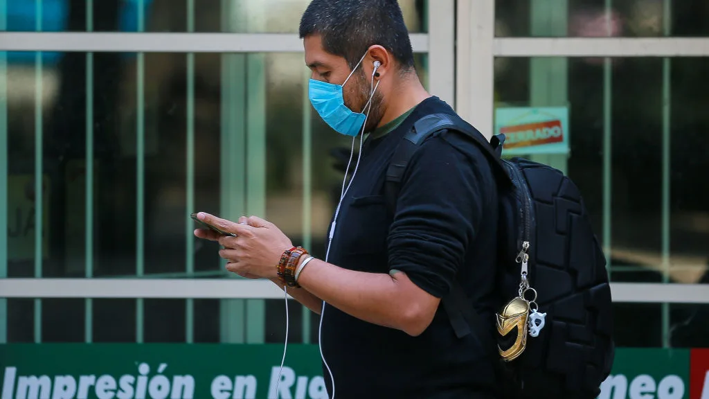 Coronavirus | Un hombre con mascarilla consulta su teléfono