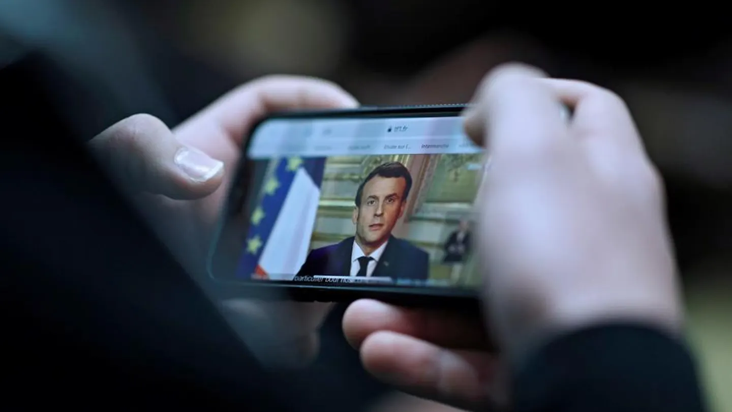 Un ciudadano sigue a través de su móvil el discurso de Emmanuel Macron Un ciudadano sigue a través de su móvil el discurso de Emmanuel Macron