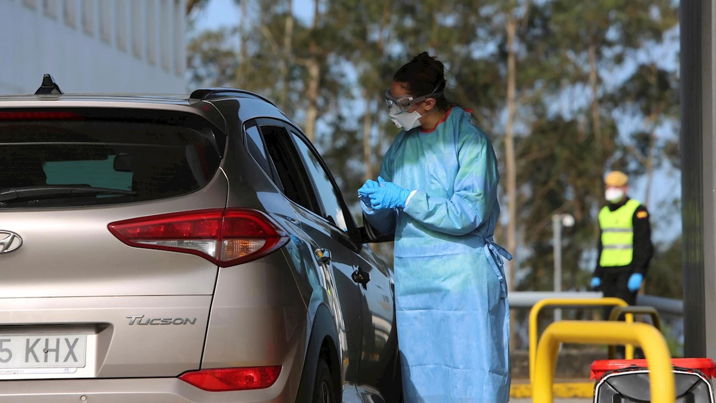 Una sanitaria junto a un coche en la crisis por coronavirus Una sanitaria junto a un coche en la crisis por coronavirus