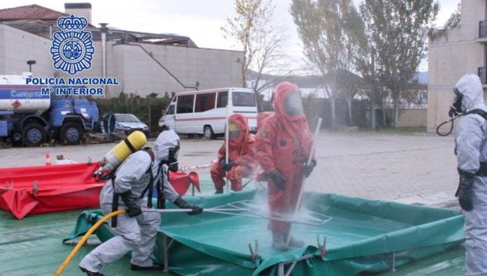 Un equipo de los TEDAX desinfectando a agentes de la Policía Nacional