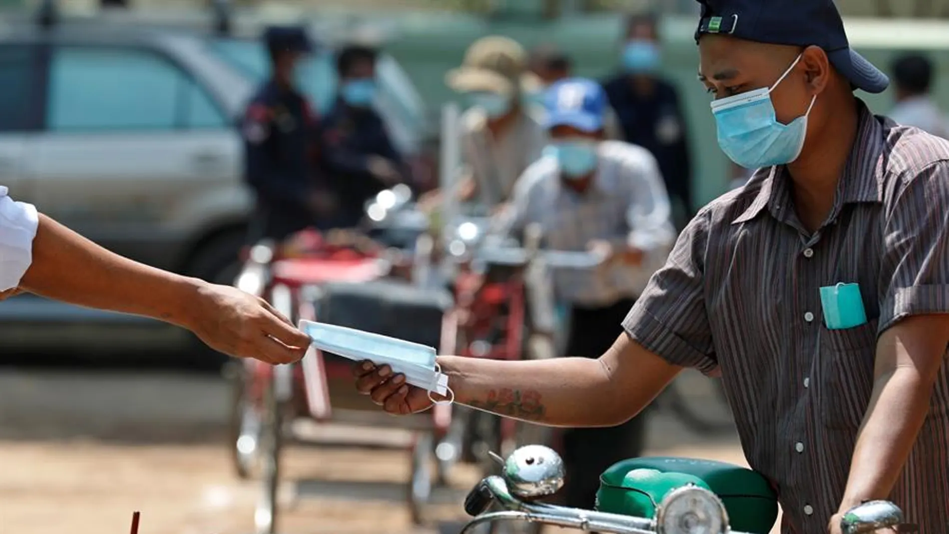 Un conductor recibe una mascarilla gratuita durante una donación de alimentos a personas con bajos ingresos en Myanmar