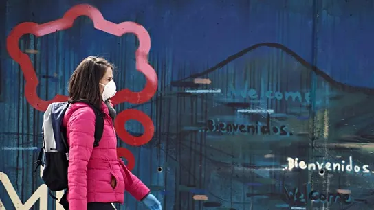 Una mujer con mascarilla y guantes camina por una calle de Ávila Una mujer con mascarilla y guantes camina por una calle de Ávila