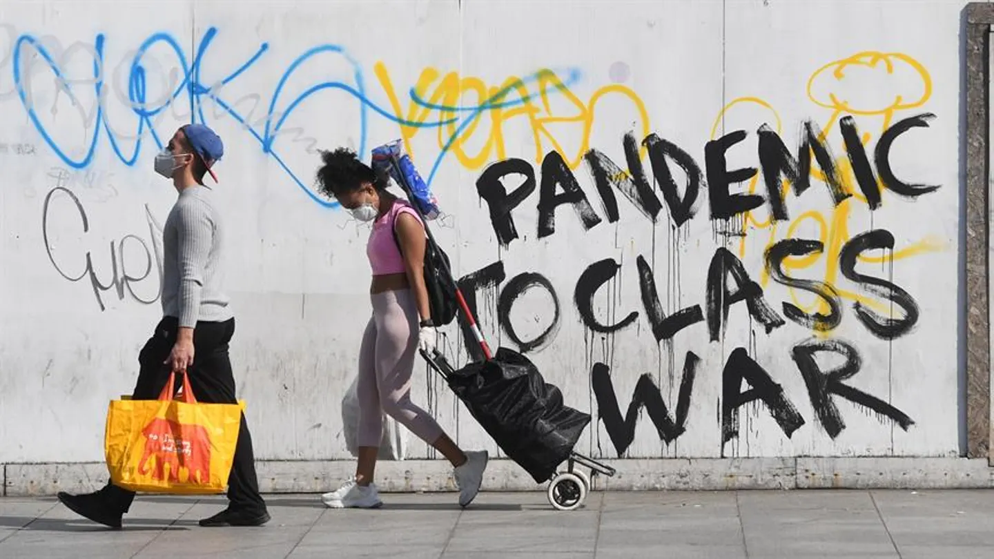 Personas con mascarilla frente a un grafitti sobre el coronavirus en Londres Personas con mascarilla frente a un grafitti sobre el coronavirus en Londres