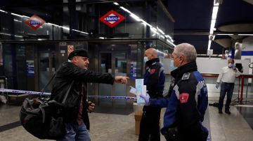 Policías entregan mascarillas en la estación de metro de Nuevos Ministerios en Madrid, este lunes. 