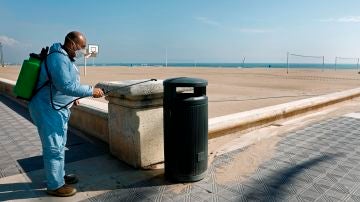 Un operario desinfecta una papelera ante una playa de la Malvarrosa (Valencia)