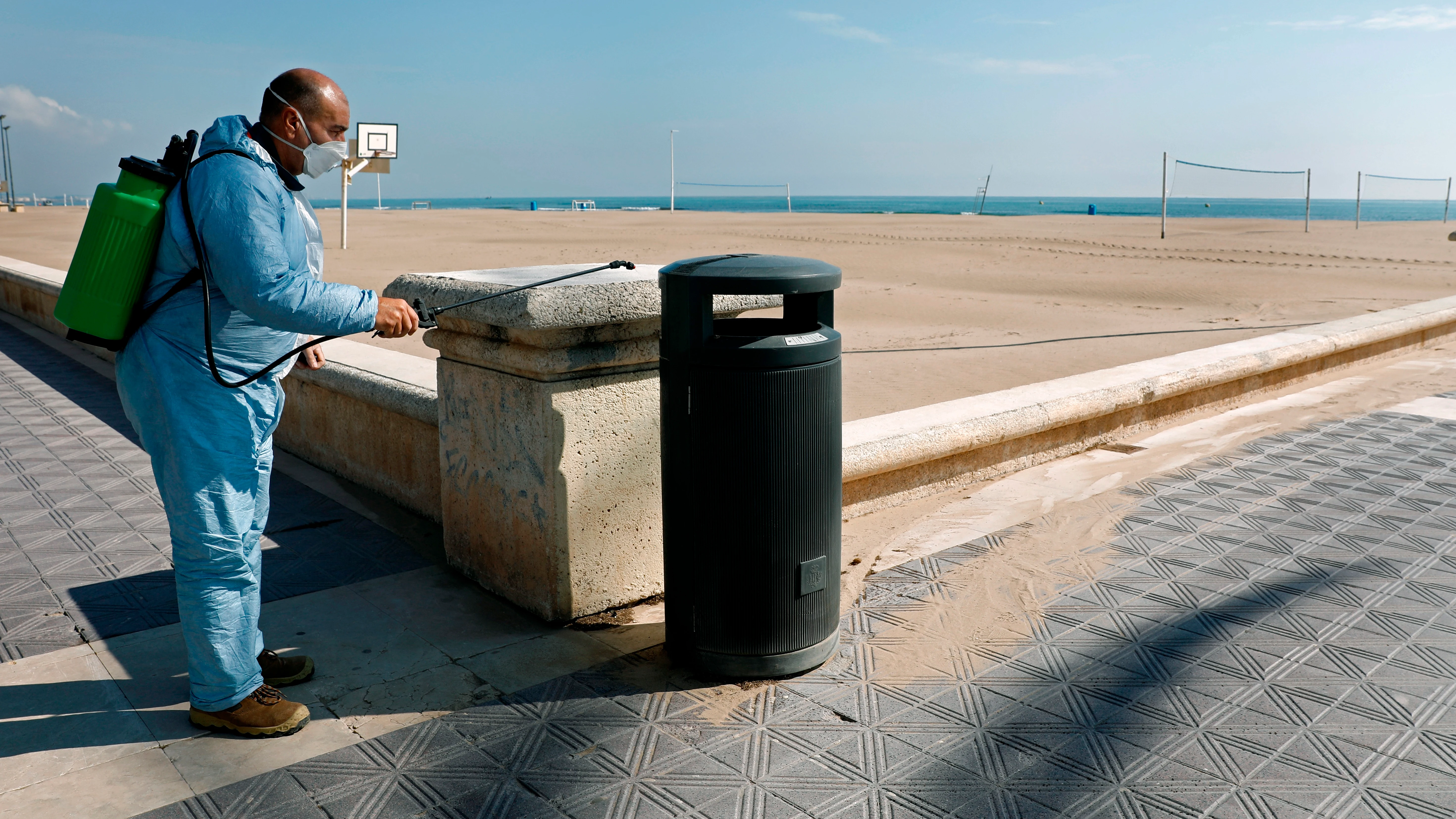 Un operario desinfecta una papelera ante una playa de la Malvarrosa (Valencia)