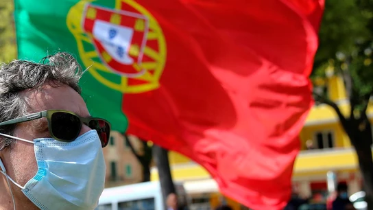 Un ciudadano pasa por delante de una bandera de Portugal Un ciudadano pasa por delante de una bandera de Portugal
