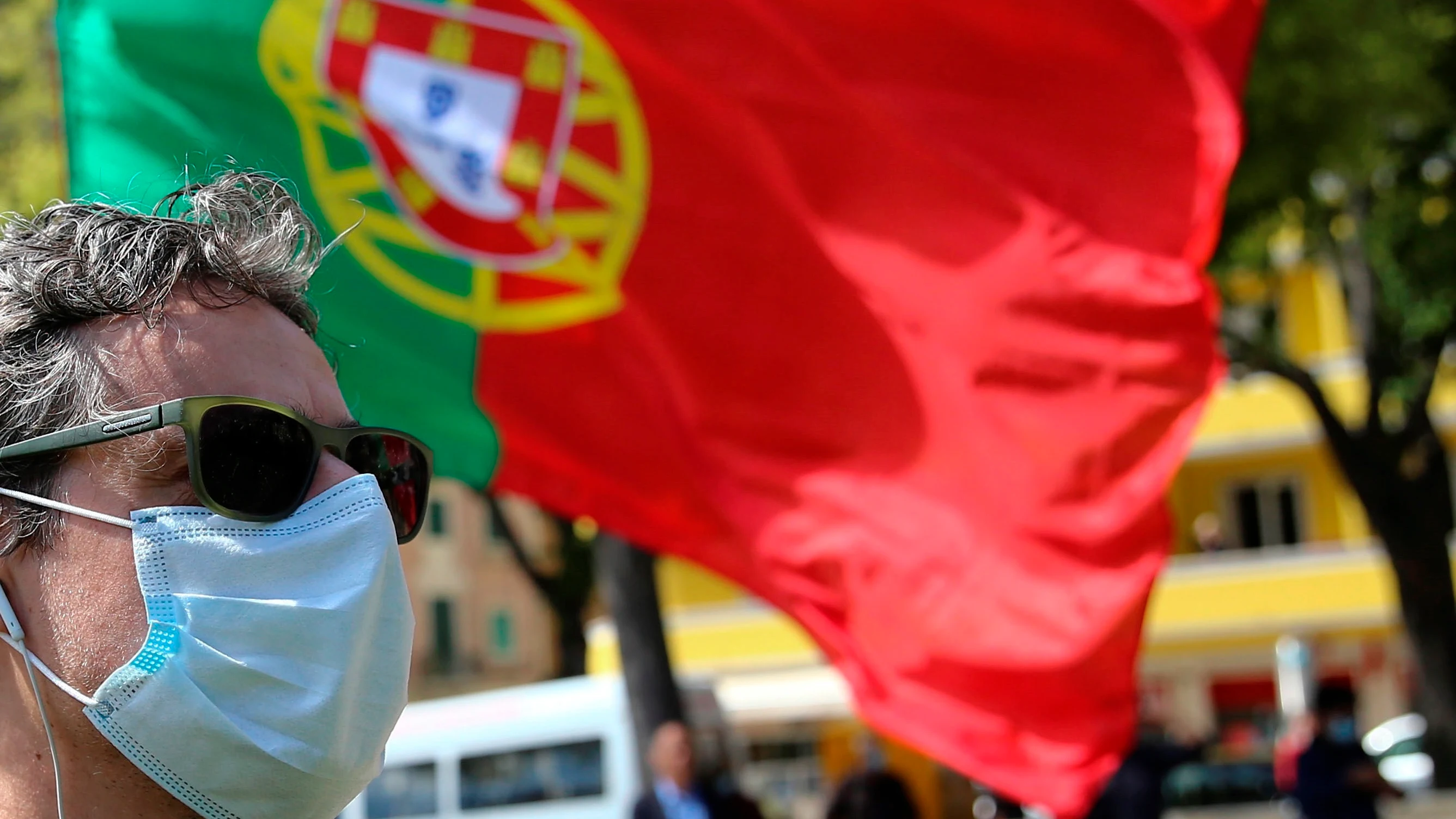 Un ciudadano pasa por delante de una bandera de Portugal