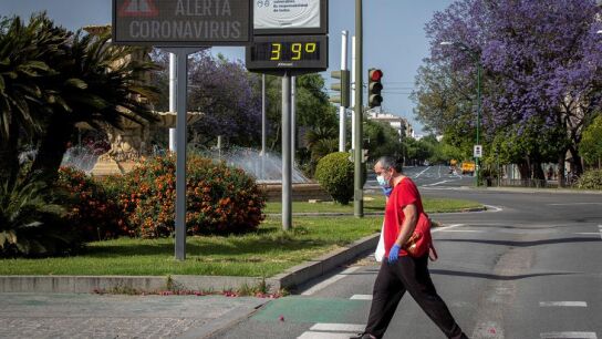 Un hombre protegido con guantes y mascarilla pasea por Sevilla bajo temperaturas de 39&ordm;C