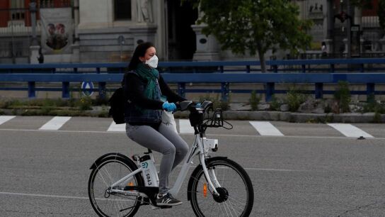 Una mujer con mascarilla y guantes usa una bici de biciMad en Madrid