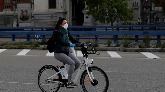 Una mujer con mascarilla y guantes usa una bici de biciMad en Madrid Una mujer con mascarilla y guantes usa una bici de biciMad en Madrid
