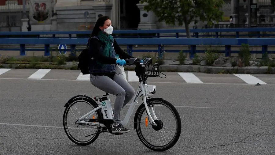 Una mujer con mascarilla y guantes usa una bici de biciMad en Madrid