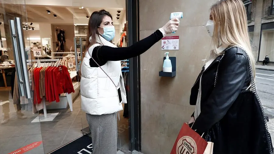 La encargada de una tienda de ropa toma la temperatura a una trabajadora