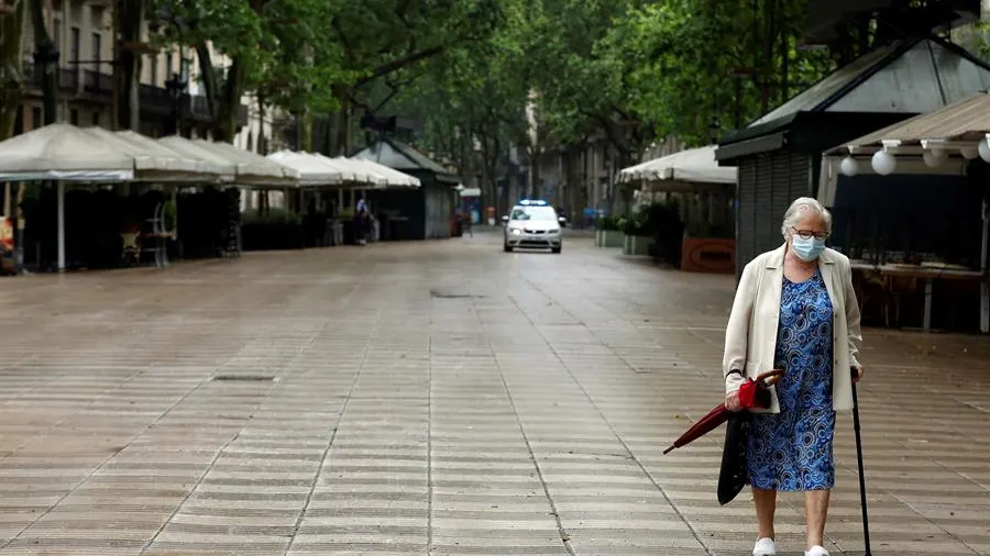 Una mujer protegida con mascarilla pasea por las Ramblas