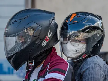Pareja en moto con mascarillas Pareja en moto con mascarillas