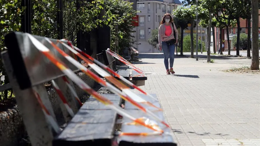 Una mujer pasea junto a unos bancos en Ponferrada