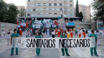 Miembros del personal sanitario del Hospital Gregorio Marañón posan con una pancarta en la que se lee "Sanitarios necesarios" durante una concentración