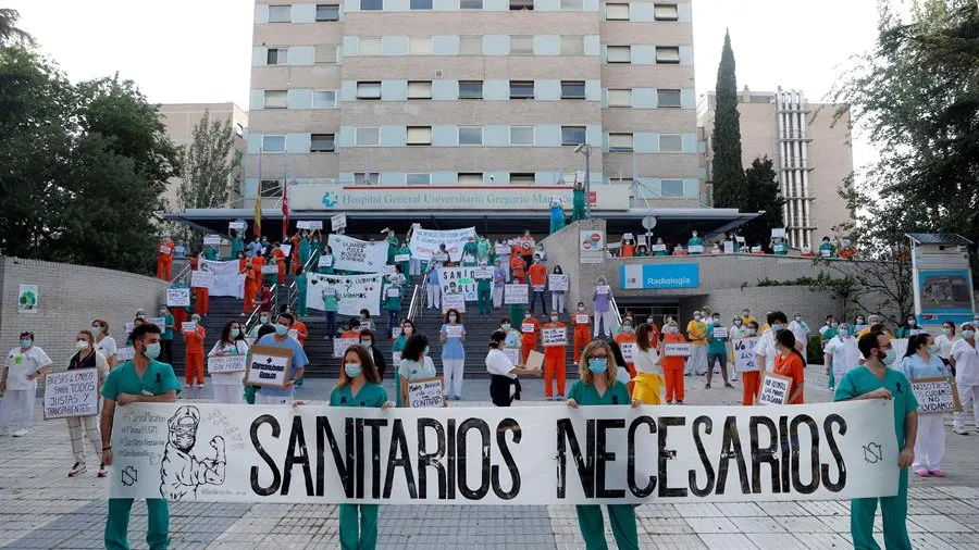 Miembros del personal sanitario del Hospital Gregorio Marañón posan con una pancarta en la que se lee "Sanitarios necesarios" durante una concentración