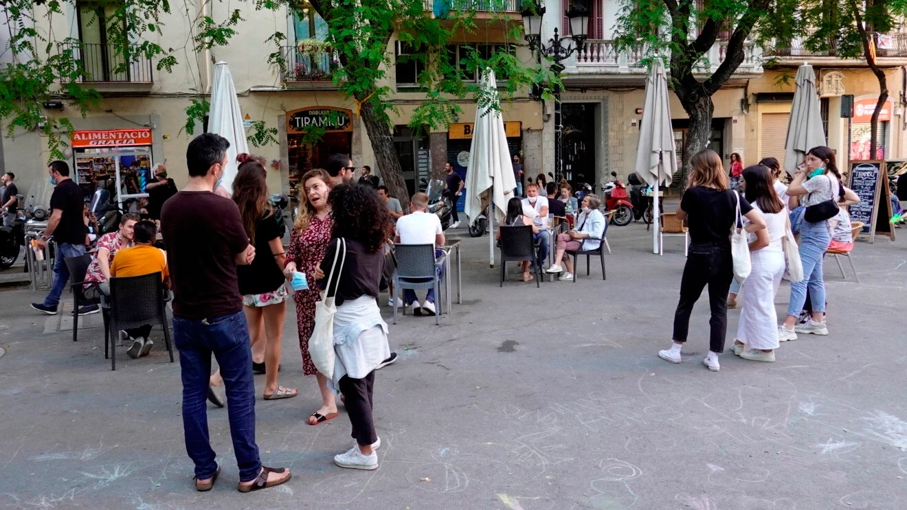 Varios jóvenes hacen cola para sentarse en una de las terrazas de la plaza de la Vila del barrio de Gracia de Barcelona