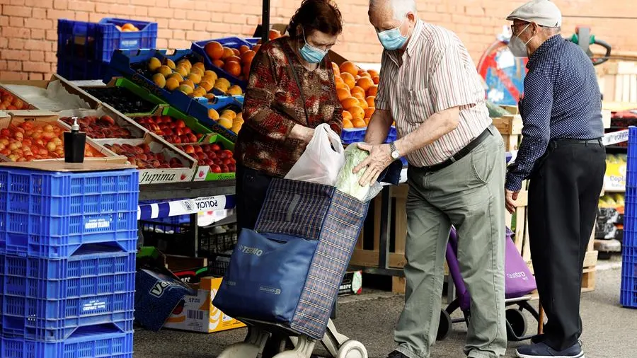 Varias personas hacen sus compras en un mercadillo en Madrid