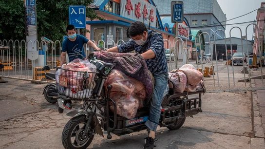Un hombre con mascarilla montado en su moto en Pekín, China Un hombre con mascarilla montado en su moto en Pekín, China