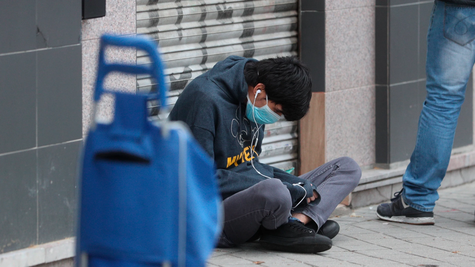 Una persona espera en la fila para recoger alimentos proporcionados por la Asociación de vecinos de Aluche, en Madrid