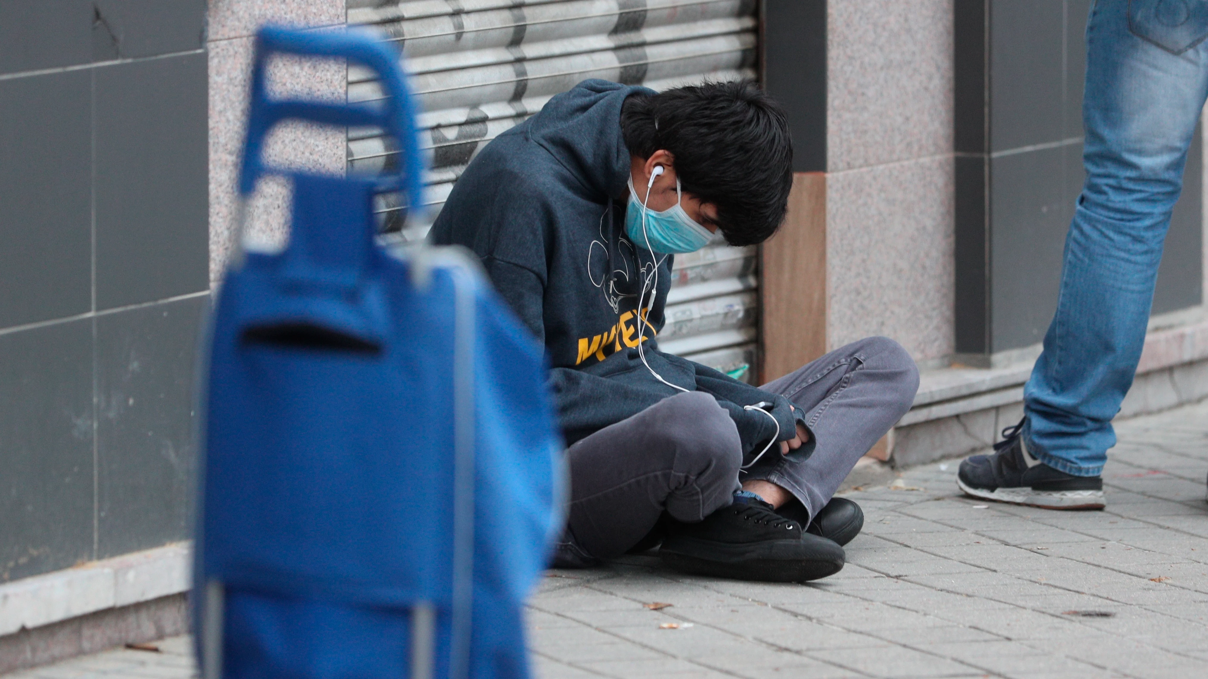 Una persona espera en la fila para recoger alimentos proporcionados por la Asociación de vecinos de Aluche, en Madrid