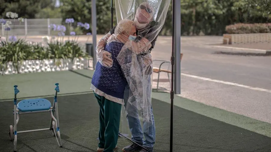 Una interna en una residencia de mayores abraza a su hijo a través de un plástico tras meses de separación por el Covid