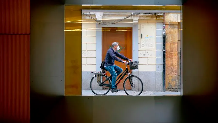 Un hombre con mascarilla pasea en bicicleta por Oviedo