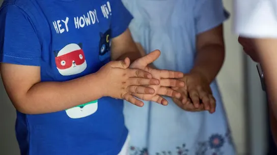 Dos niños de desinfectan las manos con gel hidroalcohólico Dos niños de desinfectan las manos con gel hidroalcohólico