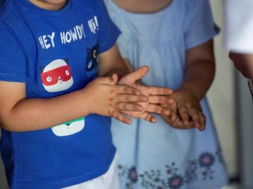 Dos niños de desinfectan las manos con gel hidroalcohólico Dos niños de desinfectan las manos con gel hidroalcohólico