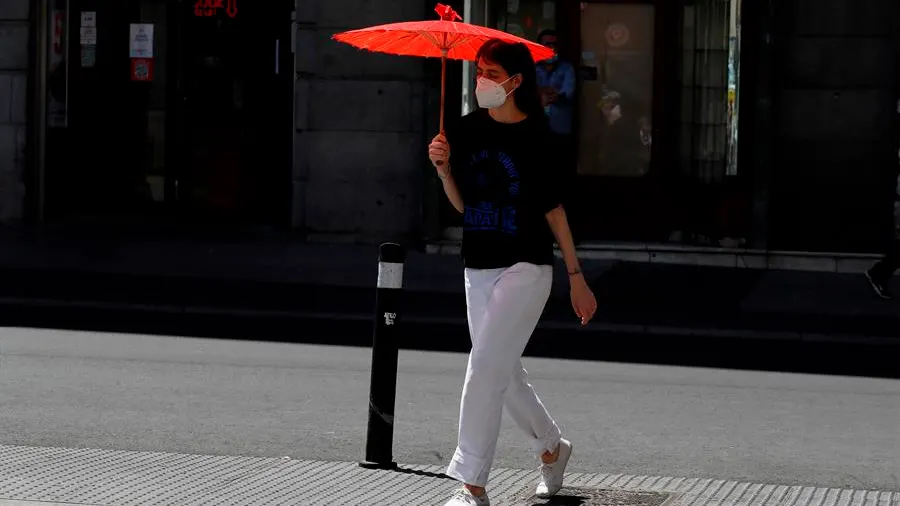 Una mujer se protege del sol con una sombrilla en el centro de Madrid. 