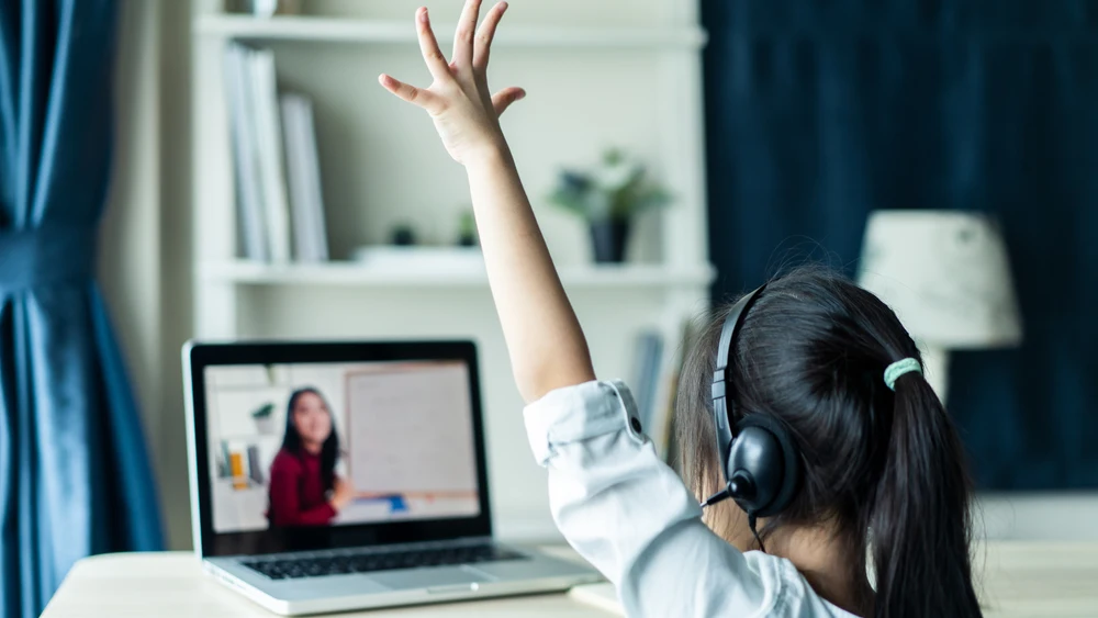 Niña levanta la mano mientras atiende en una clase 'online'