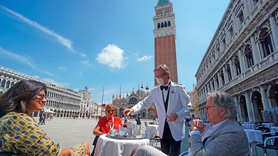 Un camarero atiende a varios clientes en una terraza Un camarero atiende a varios clientes en una terraza