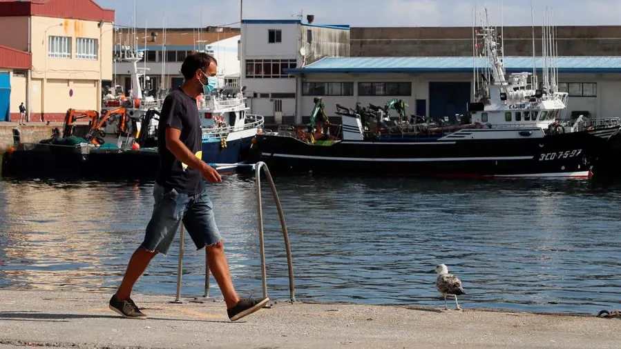 Un trabajador camina por el puerto de Burela, el municipio de A Mariña con más afectados por el brote de coronavirus.