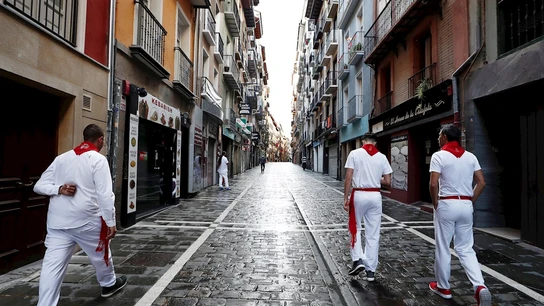 Tres corredores habituales del encierro caminan por una vacía calle Estafeta Tres corredores habituales del encierro caminan por una vacía calle Estafeta