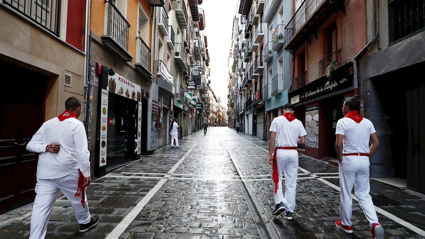 Tres corredores habituales del encierro caminan por una vacía calle Estafeta Tres corredores habituales del encierro caminan por una vacía calle Estafeta